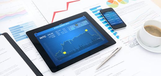 Modern business workplace with stock market data on a digital tablet, mobile banking on a smartphone and many charts and graphs on a desktop.